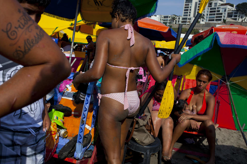 In this Jan. 24, 2013 photo, a woman breast feeds among the crowd gathered on Agua Dulce beach in Lima, Peru. On some weekends during the Southern Hemisphere summer, which runs from December until March, as many as 40,000 people a day visit the half-mile-long (kilometer-long) strip of Agua Dulce. (AP Photo/Rodrigo Abd)