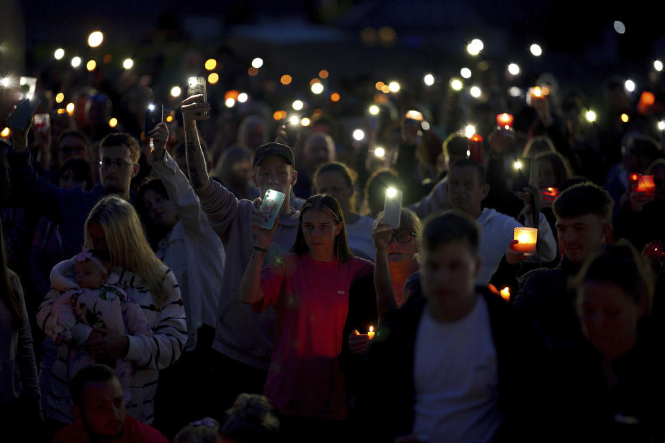 People attend a vigil for the victims of the mass shooting in Plymouth, England, Friday Aug. 13, 2021. Six people, including the offender, died of gunshot wounds in a firearms incident on Thursday evening. The police have said the gunman killed his own mother along with a three-year old girl and her father. (Ben Birchall/PA via AP)