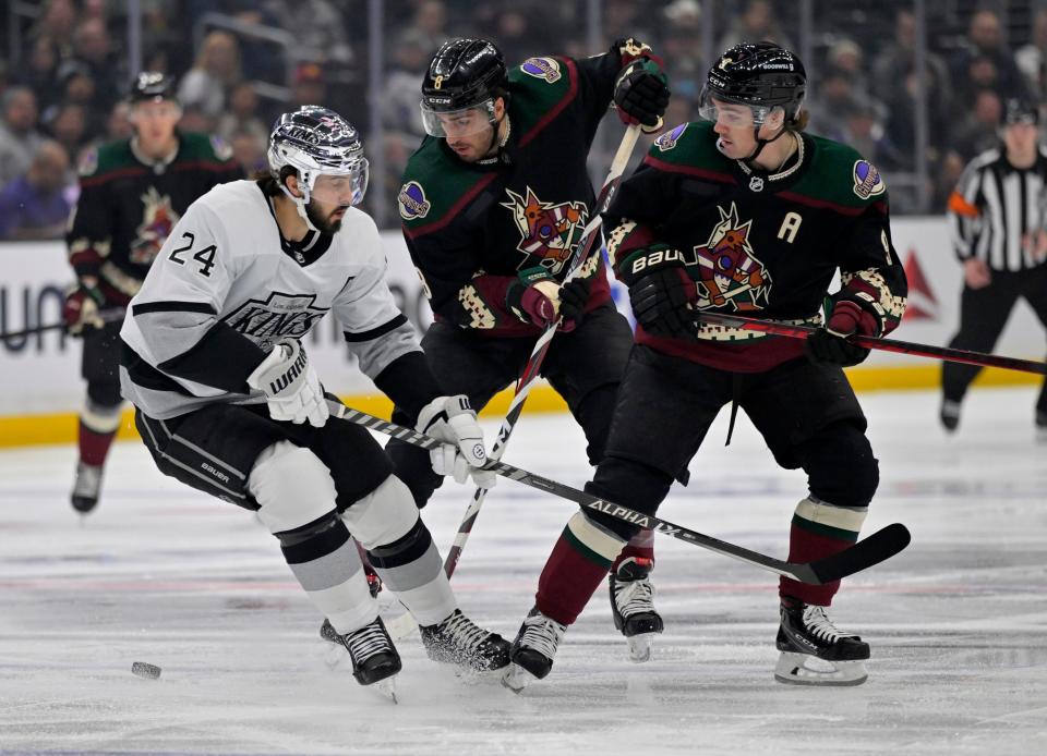 Los Angeles Kings center Phillip Danault (24), Arizona Coyotes center Nick Schmaltz (8) and right wing Clayton Keller (9) battle for the puck in the first period at Crypto.com Arena in Los Angeles on Feb. 18, 2023.