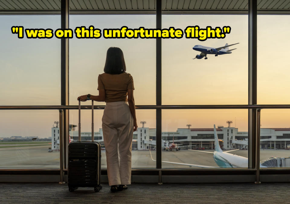 Person at airport terminal watching airplane take off, standing with luggage