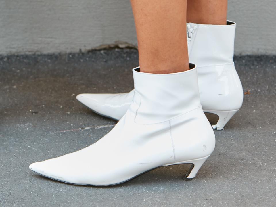 two people wearing street style outfits with decorative loafers and white ankle boots with a curved heel