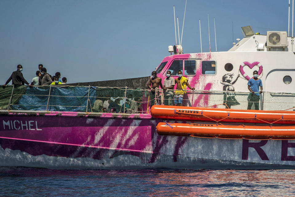 People stand on the deck of the Louise Michel rescue vessel, a French patrol boat currently manned by activists and funded by the renowned artist Banksy in the Central Mediterranean sea, at 50 miles south from Lampedusa, Friday, Aug. 28, 2020. British artist Banksy has financed a boat to rescue refugees attempting to reach Europe from north Africa. (AP Photo/Santi Palacios)