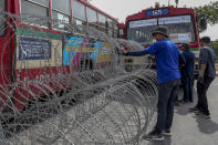 Men make barricades with buses, concreate blocks and barbed wires blocking a road heading to the Government House, office of the prime minister, ahead of a pro-democracy street march and a rally in Bangkok, Thailand Sunday, Nov. 8, 2020. (AP Photo/Rapeephat Sitichailapa)
