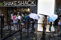 Visitors line up in the rain for the opening of the first Beijing outlet for Shake Shack in Beijing on Wednesday, Aug. 12, 2020. The U.S. headquartered burger chain is opening its first Beijing restaurant at a time when China and the U.S. are at loggerheads over a long list of issues. (AP Photo/Ng Han Guan)