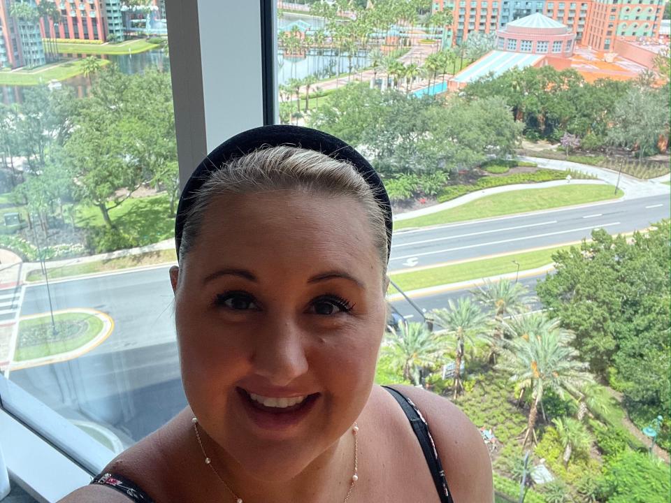 carly posing in front of the window overlooking the swan and dolphin resort at disney world