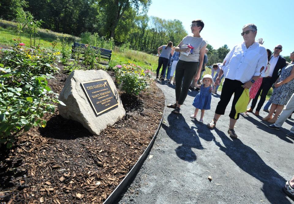 Hadley Hemingway Kogut, 17 months, granddaughter of the late Norwell conservation agent Nancy Hemingway,  is joined by Martha Gardner, left, and Amy Kogut, right, all of Maine, as they admire the garden that was dedicated in Hemingway's memory.