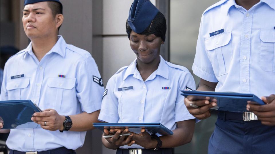 Airman 1st Class Joshua Fancisco, from the Philippines, left, Airman 1st Class D'elbrah Assamoi, from Cote D'Ivoire, center, and Airman 1st Class Jordan Flash, from Jamaica, looks at their U.S. Certificate of Citizenship after signing it following the Basic Military Training Coin Ceremony on April 26, 2023, at Joint Base San Antonio-Lackland, Texas. (Christa D'Andrea/U.S. Air Force via AP)