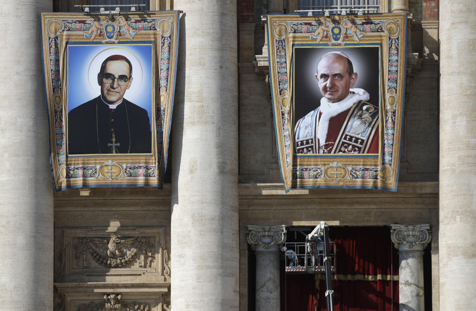 FILE - In this Friday, Oct. 12, 2018 file photo, the tapestries of Roman Catholic Archbishop Oscar Romero, left, and Pope Paul VI hang from a balcony of the facade of St. Peter's Basilica at the Vatican, Friday, Oct. 12, 2018. Pope Francis will canonize two of the most important and contested figures of the 20th-century Catholic Church, declaring Pope Paul VI and the martyred Salvadoran Archbishop Oscar Romero as models of saintliness for the faithful today. Sunday's ceremony is likely to be emotional for Francis, since he was greatly influenced by both men and privately told confidantes he wanted them made saints during his papacy. (AP Photo/Alessandra Tarantino, File)