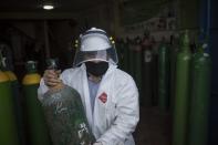 A worker delivers a refilled oxygen cylinder to Cesar Garcia outside a shop in Lima, Peru, Thursday, June 11, 2020. Garcia waited more than 7 hours to refill the oxygen cylinder which he needs for his 29-year-old stepson Mario Solis who is suffering from COVID-19. The oxygen in the cylinder itself will only last about 24 hours before it needs to be refilled. (AP Photo/Rodrigo Abd)