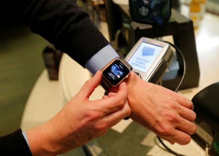 FILE PHOTO: A man uses an Apple Watch to demonstrate the mobile payment service Apple Pay at a cafe in Moscow, Russia, October 3, 2016. Picture taken October 3, 2016. REUTERS/Maxim Zmeyev/File Photo