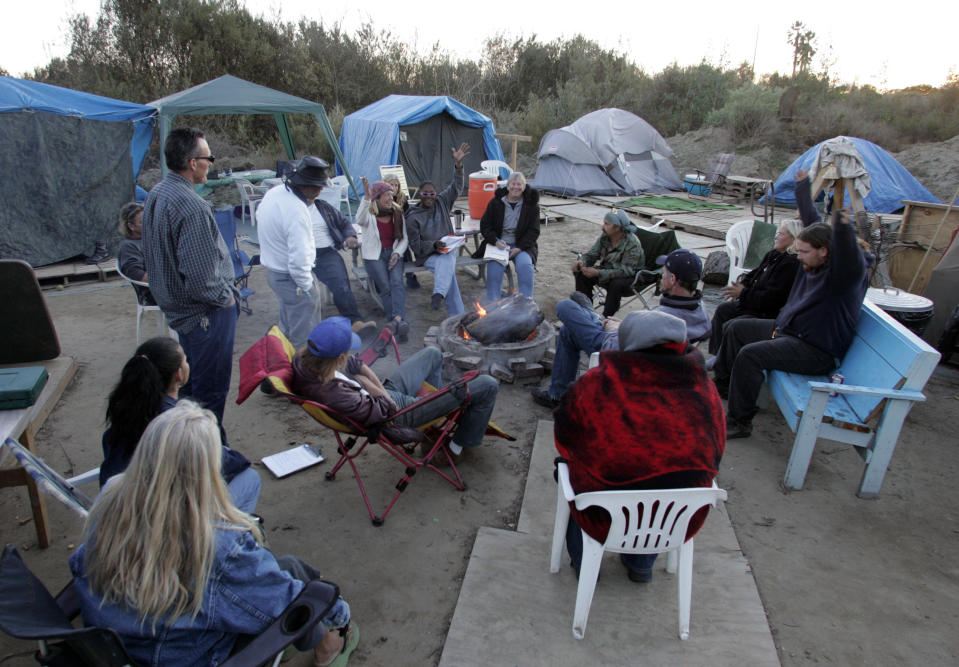 Camp residents vote on an issue. Homeless residents of River Haven, a tent encampment near the banks of the Santa Clara river, held a community which is headed by a camp council. The council meets weekly with all residents. The residents discussed several issues ranging from writeups for breaking camp rules to ideas for a Secret Santa gift exchange.  (Photo by Stephen Osman/Los Angeles Times via Getty Images)
