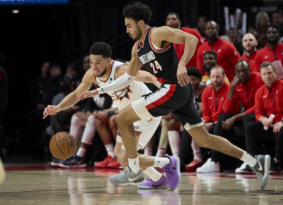 Phoenix Suns guard Devin Booker, left, and Portland Trail Blazers forward Justin Minaya (24) reach for the ball during the second half of an NBA basketball game in Portland, Ore., Sunday, Jan. 14, 2024. (AP Photo/Craig Mitchelldyer)