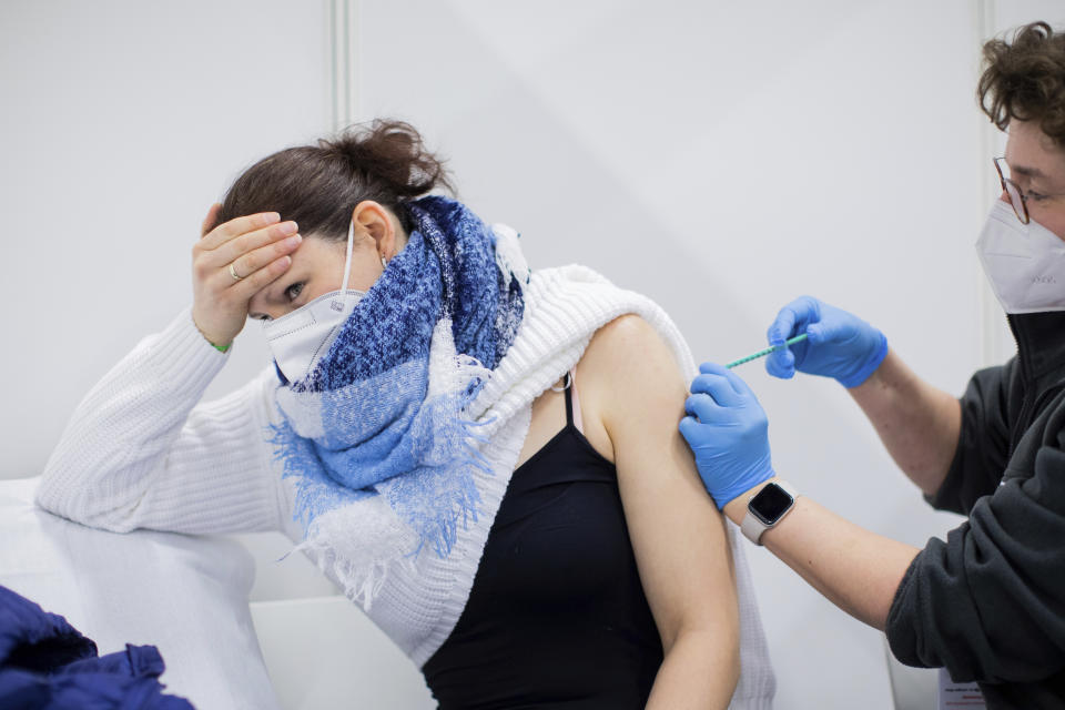 Bianca Ahlemeier (32), a childminder in home daycare with five children, is vaccinated with AstraZeneca's vaccine by a doctor at the vaccination centre in Koelnmesse, Cologne, Germany, Monday, March 8, 2021. From today on nursery school teachers, child minders, some teachers and police officers, as well as people in workshops for disabled people, will be vaccinated with AstraZeneca's preparation. (Rolf Vennenbernd/dpa/ via AP)