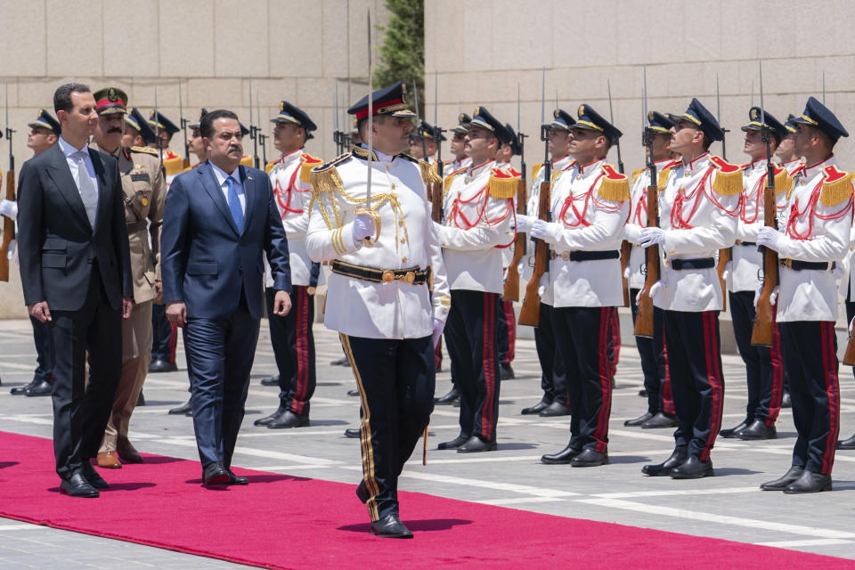 In this photo released by the Syrian official news agency SANA, Syrian President Bashar Assad, left, and Iraq's Prime Minister Mohammed Shia al-Sudani review a military honour guard during a welcome ceremony in Damascus, Syria, Sunday, July 16, 2023. Iraq's prime minister held talks Sunday with Syrian President Bashar Assad in Damascus during the first such trip by an Iraqi premier to the war-torn country since the 12-year conflict began. (SANA via AP)