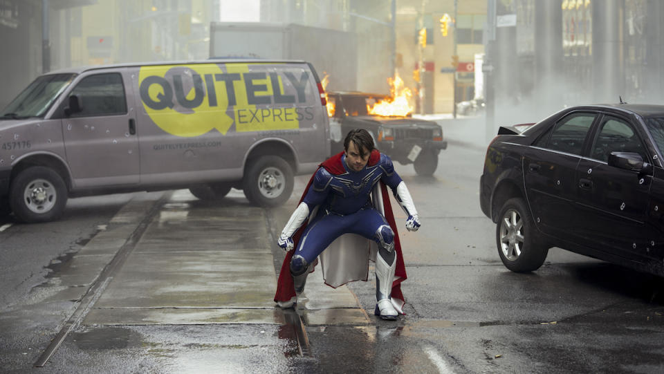 Brandon Sampson dressed in superhero clothes stands in the middle of a rainy street in Jupiter's Legacy.