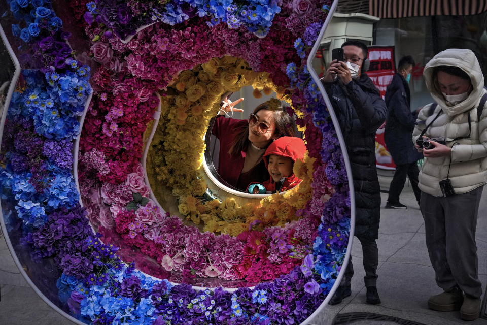 A woman and a child pose a souvenir photo with a rabbit shaped floral decoration at a pedestrian shopping street at Qianmen on the first day of the Lunar New Year holiday in Beijing, Sunday, Jan. 22, 2023. People across China rang in the Lunar New Year on Sunday with large family gatherings and crowds visiting temples after the government lifted its strict "zero-COVID" policy, marking the biggest festive celebration since the pandemic began three years ago. (AP Photo/Andy Wong)