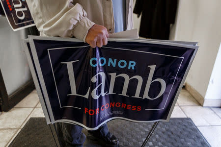 A Carnegie resident leaves a campaign event for Congressional candidate Conor Lamb carrying a yard sign showing support for the Democratic candidate in Carnegie, Pennsylvania, U.S., February 16, 2018. Picture taken February 16, 2018. REUTERS/Maranie Staab