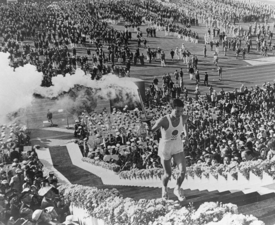 General view as Yoshinori Sakai, a student born in Hiroshima on the day the first atomic bomb devastated the city, carries the torch up the stairs to light the cauldron during the opening ceremony for the 1964 Tokyo Summer Olympic Games.