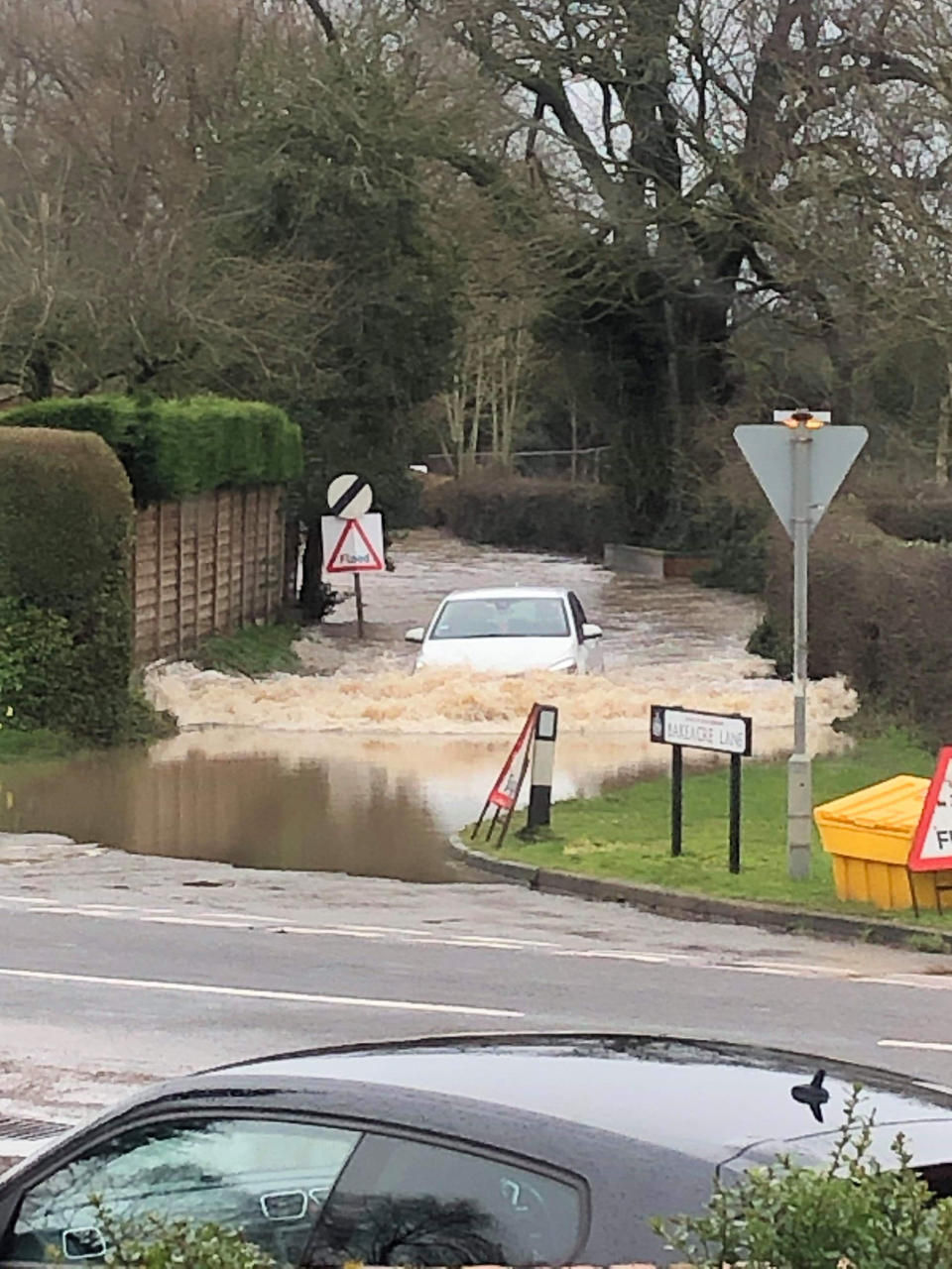 A car drives through a flooded road in the village of Findern in Derbyshire. (PA)