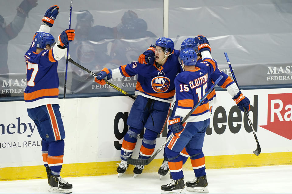 Teammates flock to congratulate New York Islanders center Mathew Barzal (13) after Barzal scored a goal during the third period of an NHL hockey game, Thursday, Feb. 11, 2021, in Uniondale, N.Y. From left are Islanders center Anders Lee (27), Barzal, right wing Cal Clutterbuck (15) and defenseman Ryan Pulock (6).(AP Photo/Kathy Willens)