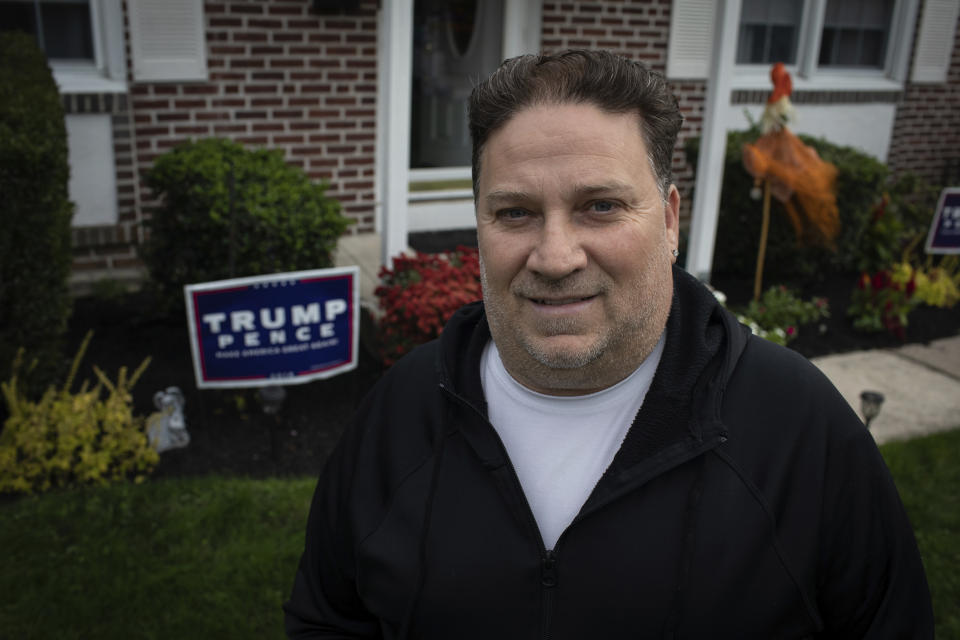 Scott Brady stands in front of his house with a Trump campaign sign in Springfield, Pa. on Wednesday, Oct. 28, 2020. Once a Democrat, Brady says he switched parties to vote for Donald Trump in 2016, and plans to vote for him again in 2020. (AP Photo/Robert Bumsted)