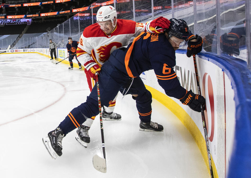 Edmonton Oilers' Adam Larsson (6) and Calgary Flames' Matthew Tkachuk (19) battle in the corner during the first period of an NHL hockey game, Thursday, April 29, 2021 in Edmonton, Alberta. (Jason Franson/Canadian Press via AP)