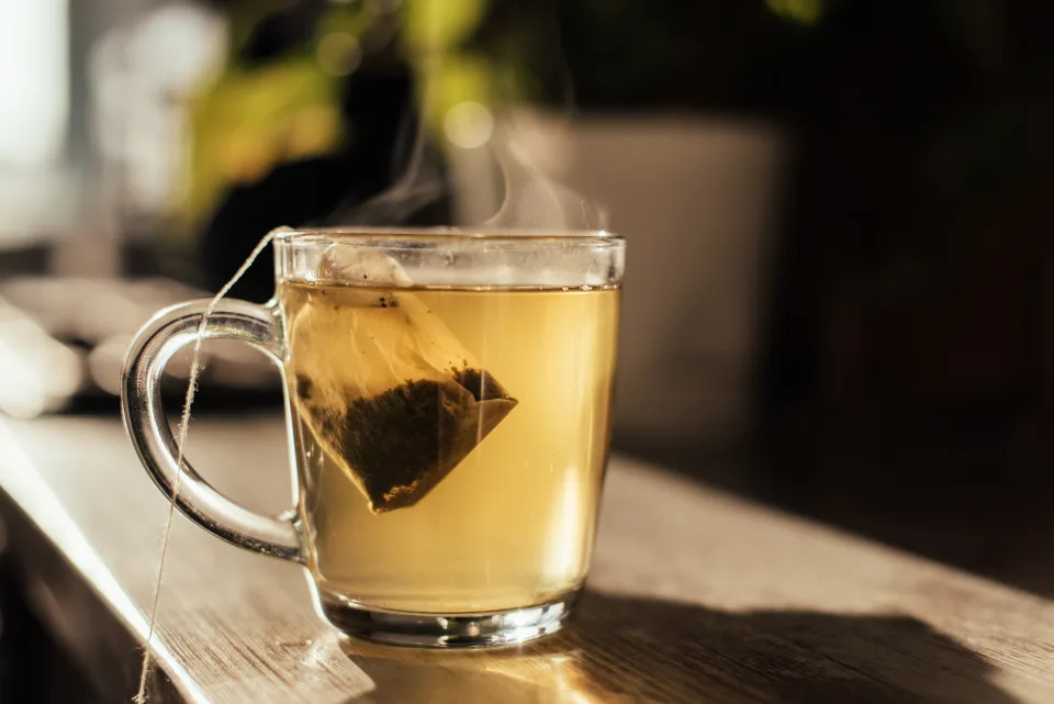 Putting tea bag into glass cup full of hot water