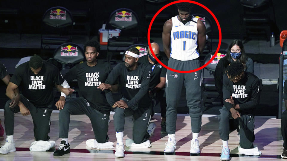 Jonathan Isaac is pictured standing during the national anthem, while his teammates can be seen alongside taking a knee in protest.