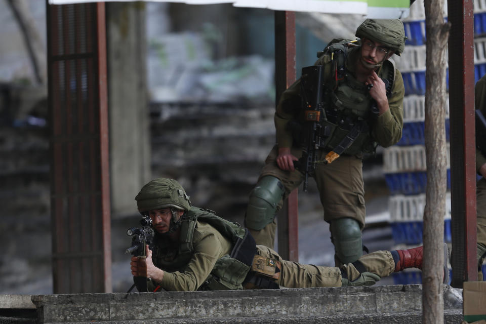 Israeli soldiers take aim at Palestinian protesters during clashes in the West Bank city of Hebron, Thursday, Feb. 6, 2020. Israeli forces have killed two Palestinians in clashes in the occupied West Bank and a third in Jerusalem after he opened fire at a police officer. The killings came hours after a car-ramming attack elsewhere in the city Thursday wounded 12 Israeli soldiers. Tensions have soared following last week's release of President Donald Trump's Mideast initiative, which greatly favors Israel and was rejected by the Palestinians. (AP Photo/Majdi Mohammed)