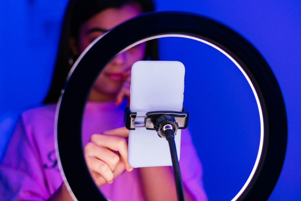 A girl standing in front of a smartphone on a ring light