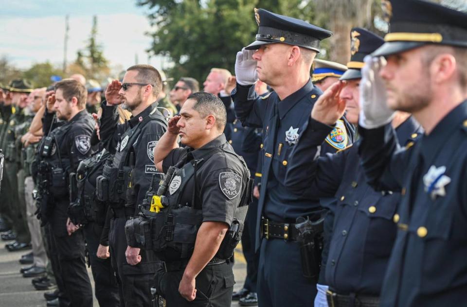 Officers from Selma and around the San Joaquin Valley salute during a service to dedicate a memorial to fallen Selma Police Officer Gonzalo Carrasco Jr. who was killed in the line of duty one year ago, at the Selma Police Department on Wednesday, Jan. 31, 2024. CRAIG KOHLRUSS/ckohlruss@fresnobee.com