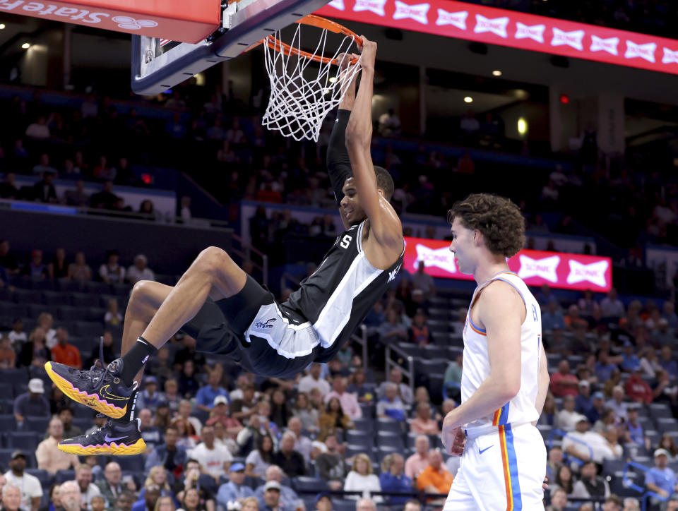 San Antonio Spurs center Victor Wembanyama, left, dunks next to Oklahoma City Thunder guard Josh Giddey, right, in the first half of a preseason NBA basketball game Monday, Oct. 9, 2023, in Oklahoma City. (AP Photo/Sarah Phipps)