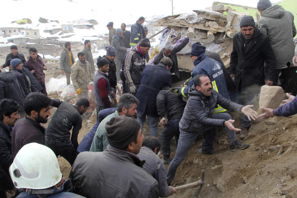 People remove debris and try to reach people trapped under a collapsed house after an earthquake hit villages in Baskale town in Van province, Turkey, at the border with Iran, Sunday, Feb. 23, 2020. Turkish Interior Minister Suleyman Soylu said numerous people have been killed and several others wounded in Sunday's quake.(IHA via AP)