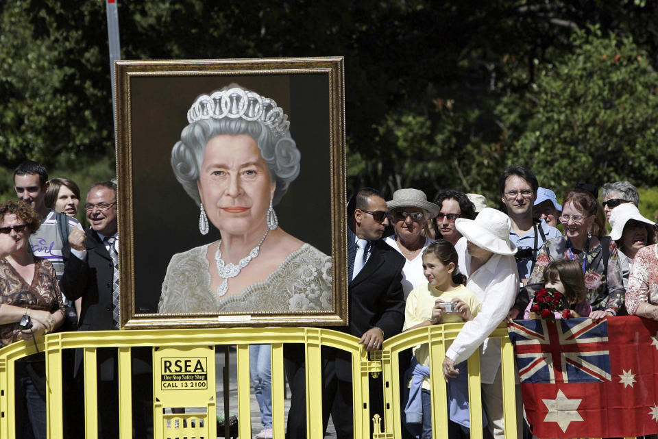 FILE - Wellwishers holding a portrait of Britain's Queen Elizabeth II wait for her arrival in Melbourne, Australia, Wednesday March 15, 2006. After seven decades on the throne, Queen Elizabeth II is widely viewed in the U.K. as a rock in turbulent times. But in Britain’s former colonies, many see her as an anchor to an imperial past whose damage still lingers. (AP Photo/Rick Stevens, File)