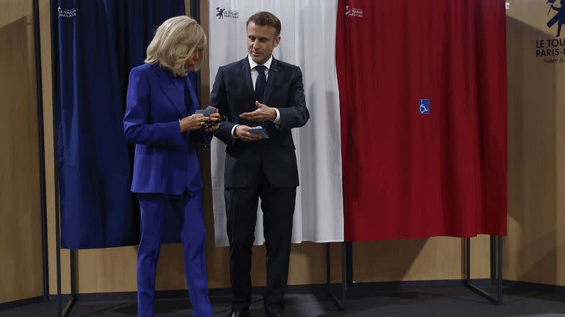French President Emmanuel Macron and his wife Brigitte Macron leave the voting booth before voting for the second round of the legislative elections 