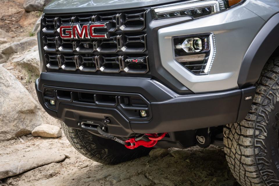 lower shot of the 2024 gmc canyon at4x aev’s stamped steel front bumper and red recovery hooks