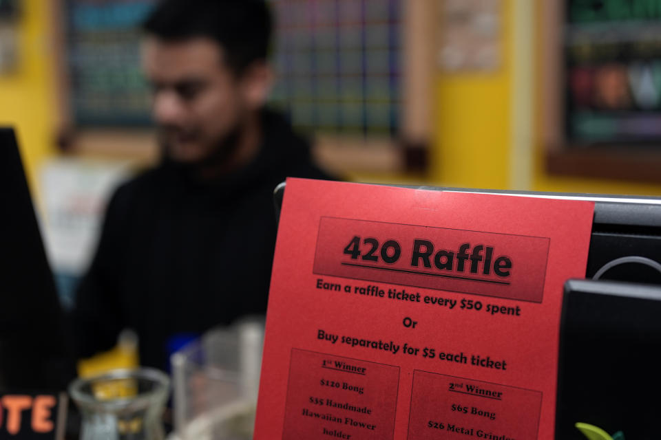 Budtender Rey Cruz rings up a customer as a 420 raffle sign is taped to a register at the Marijuana Paradise on Friday, April 19, 2024, in Portland, Ore. (AP Photo/Jenny Kane)