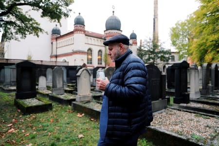 The head of Halle's Jewish community, Max Privorozki, holds a candle as he walks in a cemetery at synagogue in Halle