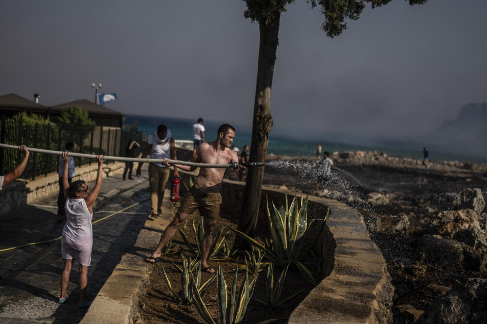 FILE - Mathias Heuhel, 30, from Germany, and other people, try to extinguish a fire, near the seaside resort of Lindos, on the Aegean Sea island of Rhodes, southeastern Greece, on Monday, July 24, 2023. Greece’s resort island of Rhodes is nursing its wounds after 11 days of devastating wildfires. (AP Photo/Petros Giannakouris, File)