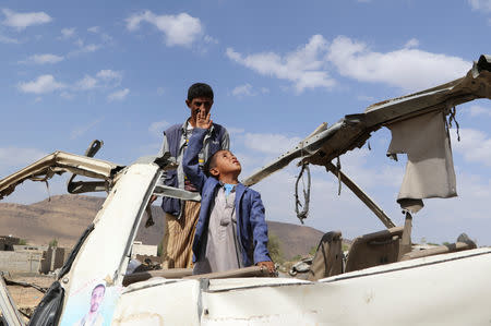 Abdullah al-Khawlani stands with his son, Hafidh, who survived a Saudi-led air strike stand on the wreckage of a bus destroyed by the strike in Saada, Yemen September 4, 2018. Another son of al-Khawlani was killed by the strike. Picture taken September 4, 2018. REUTERS/Naif Rahma