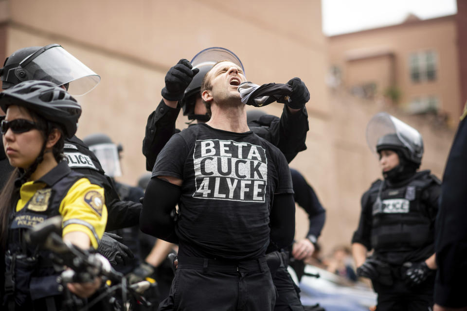 Police officers detain a protester against right-wing demonstrators following an "End Domestic Terrorism" rally in Portland, Ore., on Saturday, Aug. 17, 2019. Although the main protest remained largely peaceful, some skirmishes erupted in the following hours and police detained multiple protesters. (AP Photo/Noah Berger)