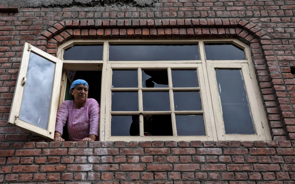 A Kashmiri woman looks out from a window of her house which was allegedly damaged by Indian security after clashes between protesters and the security forces - REUTERS