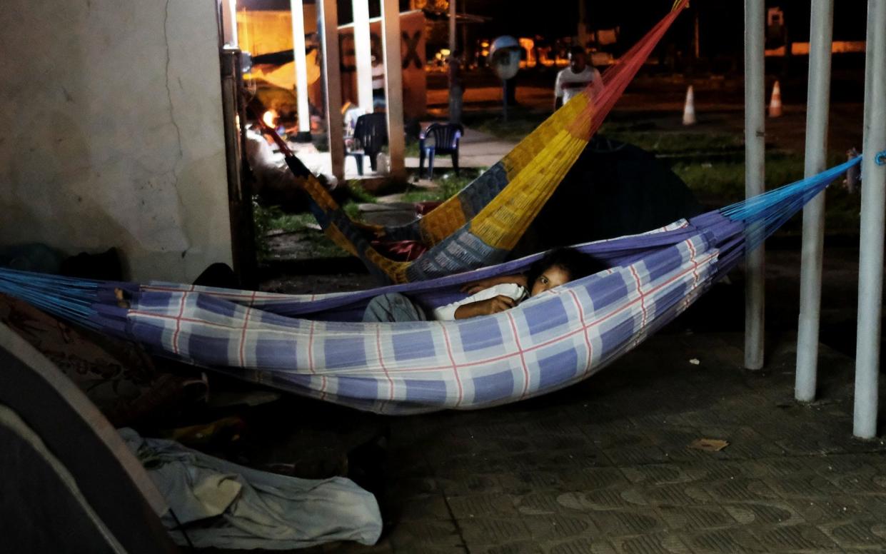 Venezuelan people rest in hammocks along the street as they wait to show their passports or identity cards next day at the Pacaraima border control - REUTERS