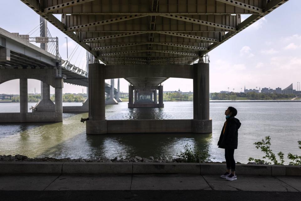 Girl stands under a bridge over a river