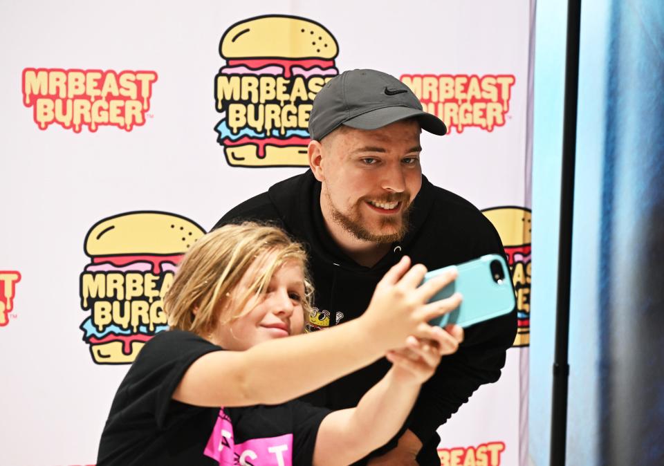 MrBeast takes a selfie with a fan at a MrBeast Burger event.