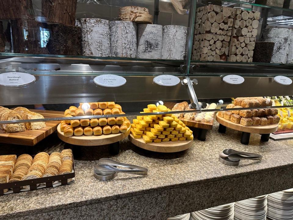 Bread section of Bacchanal buffet with cracker disaply and stacks of corn bread, brioche rolls, and more