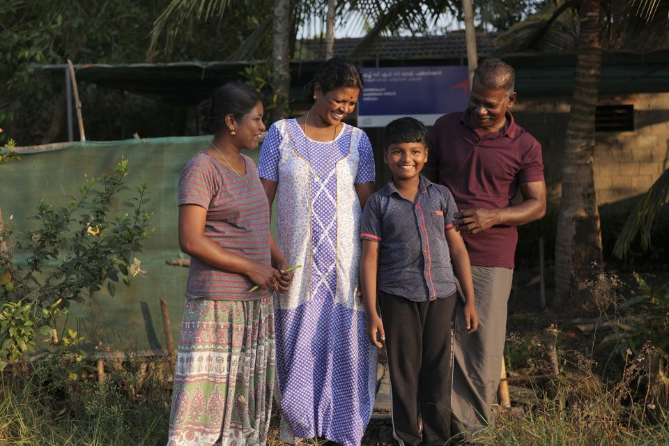 T. P. Murukesan poses with his family, from left, daughter Nimitha Manoj, wife Geetha Murukesan, grandson T. M. Akanitth at their home on Vypin Island in Kochi, Kerala state, India, on March 4, 2023. Known locally as Mangrove Man, Murukesan has turned to planting the trees along the shores to counter the impacts of rising waters on his home. (AP Photo/Shawn Sebastian)