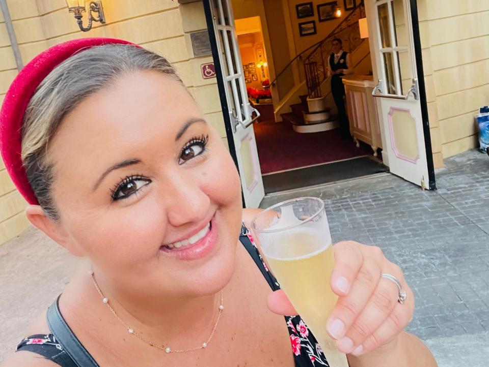 Author holding glass of champagne in front of Monsieur Paul.