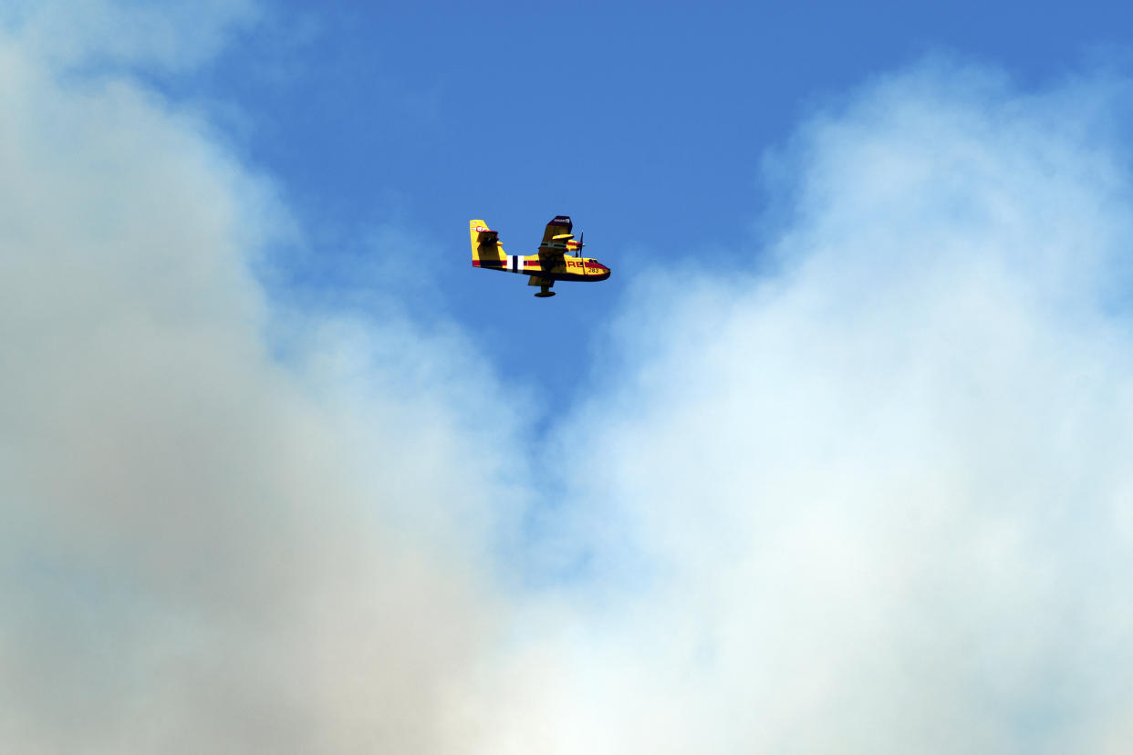 A firefighting plane flies in front of a plume of smoke near Las Vegas, N.M., on Tuesday, May 3, 2022. Flames raced across more of New Mexico's pine-covered mountainsides Tuesday, charring more than 217 square miles (562 square kilometers) over the last several weeks. (AP Photo/Thomas Peipert)