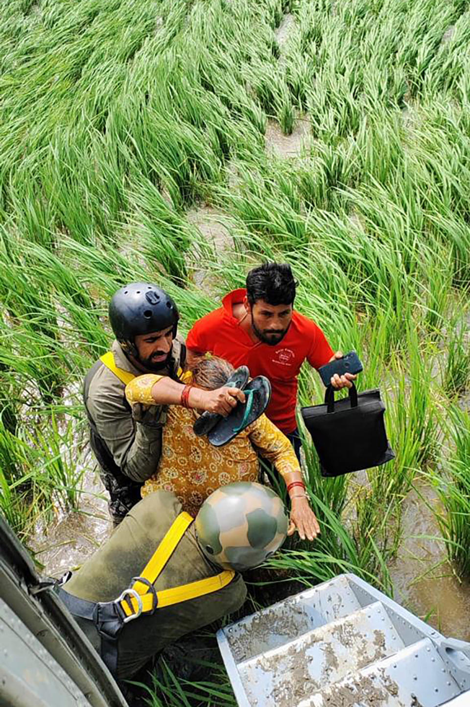 In this photo provided by the Indian air force, air force personnel help an elderly woman to be airlifted from a flood-affected area in Himachal Pradesh state, India, August 2023. Days of relentless rain in India’s Himalayan region have killed more than 70 people this week, a government official said Thursday, as a heavy monsoon triggered landslides and flash floods that have submerged roads, washed away buildings and left residents scrambling for safety.(Indian Air Force via AP)